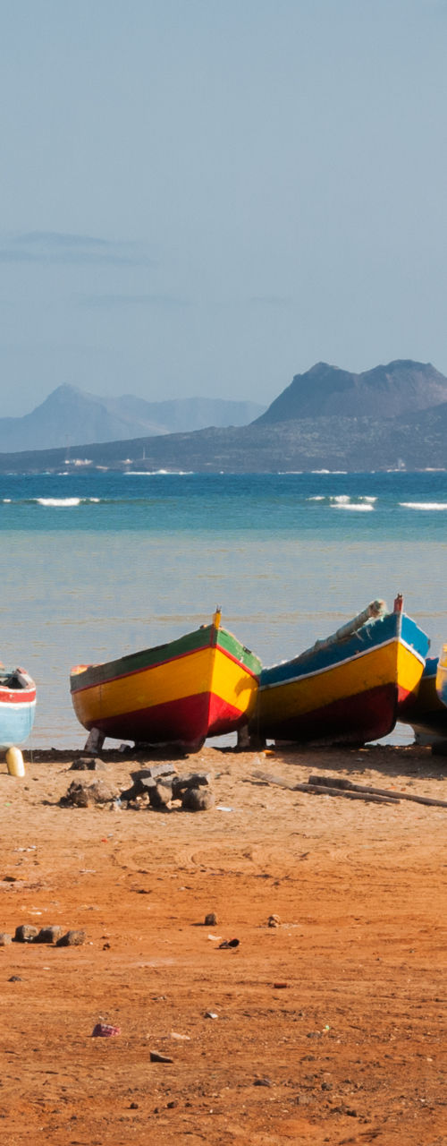 Colorful boats on sandy beach with ocean view