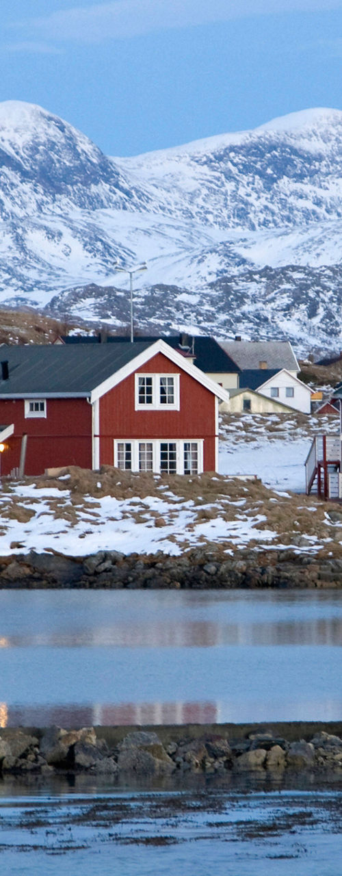 Red cabins by snowy mountain lake