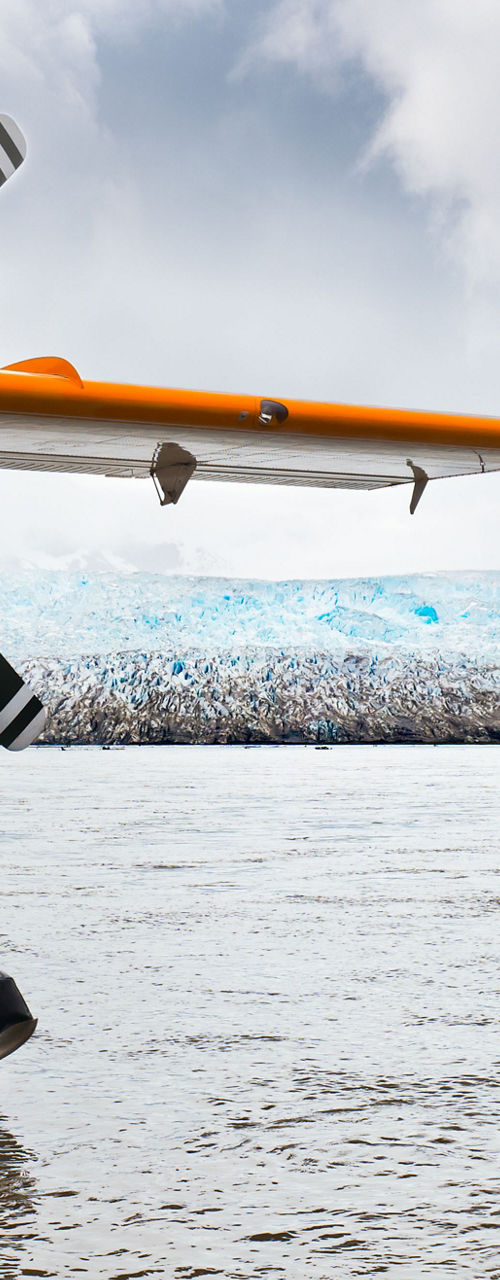 Orange seaplane docked near icy glacier