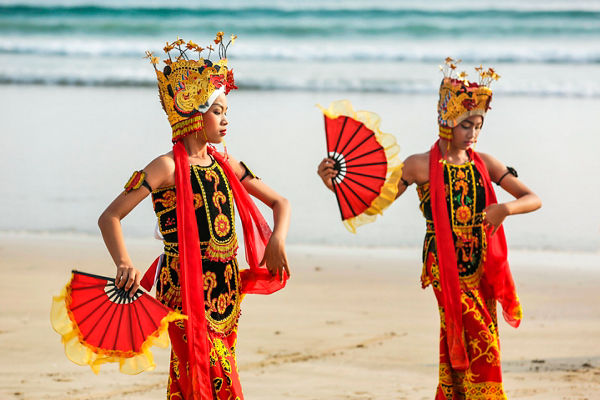 Traditional dancers with red fans on beach