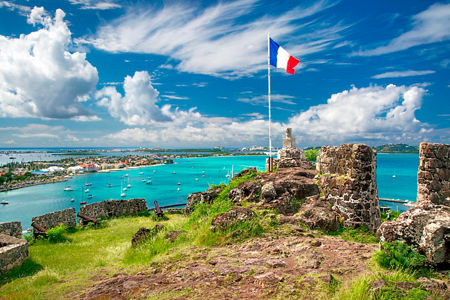 French flag atop historic coastal ruins
