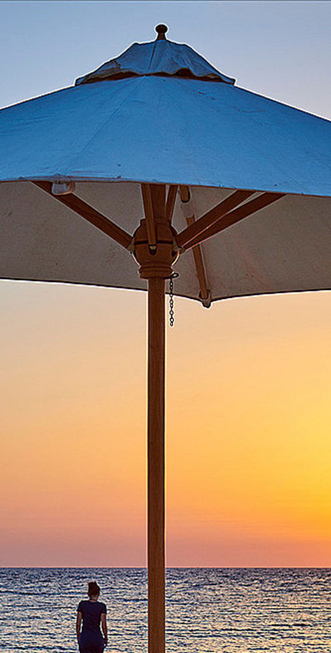 Beach sunset with lounge chairs and umbrella