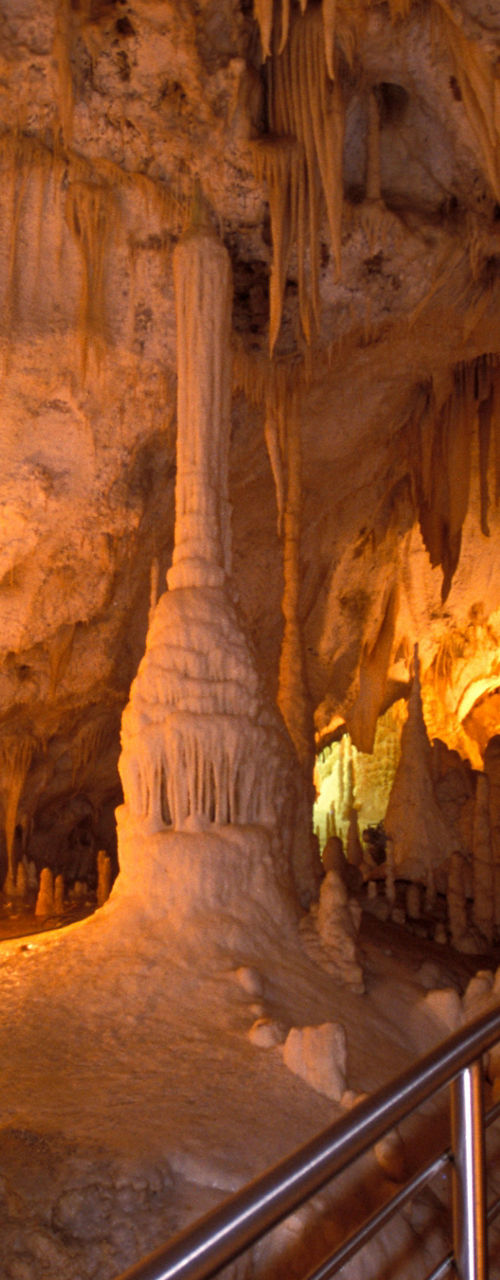 Illuminated cave with stalactites and walkway