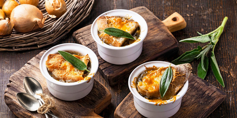 Rustic onion soup in white ramekins