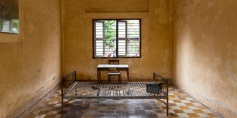 Empty prison cell with metal bed frame