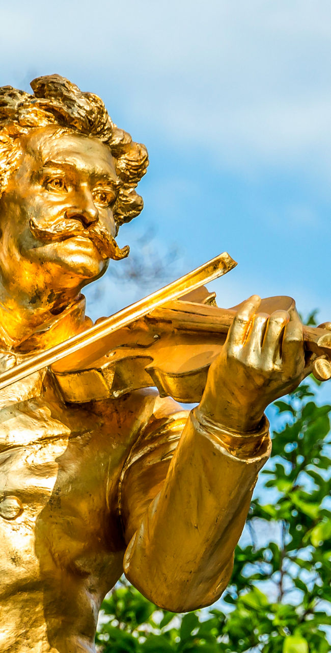 Golden statue of violinist in park setting