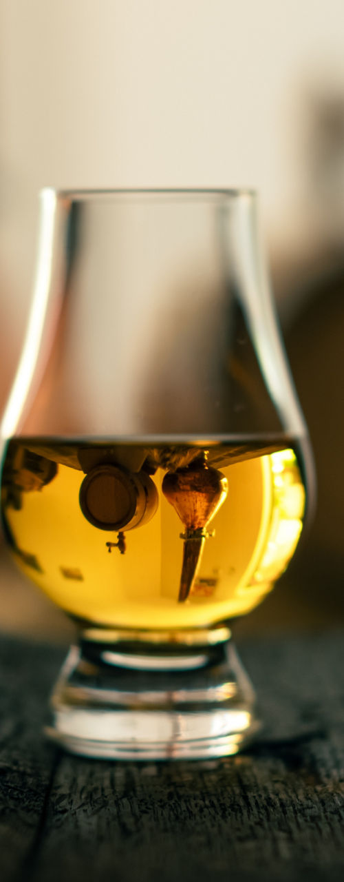 Whiskey glass on barrel with distillery setup