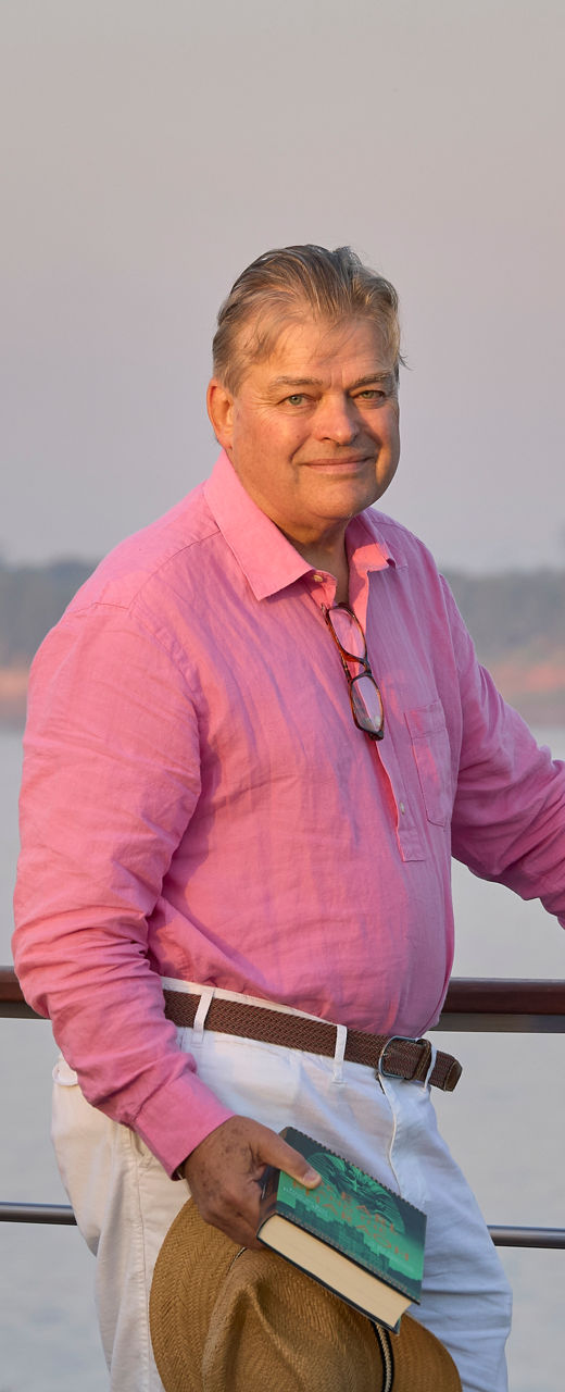 Man in pink shirt by riverside railing