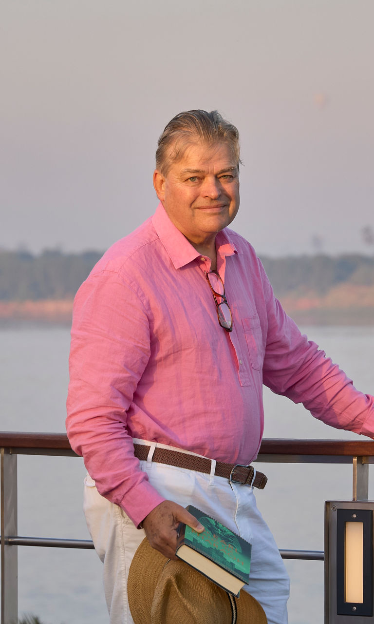 Man in pink shirt by riverside railing