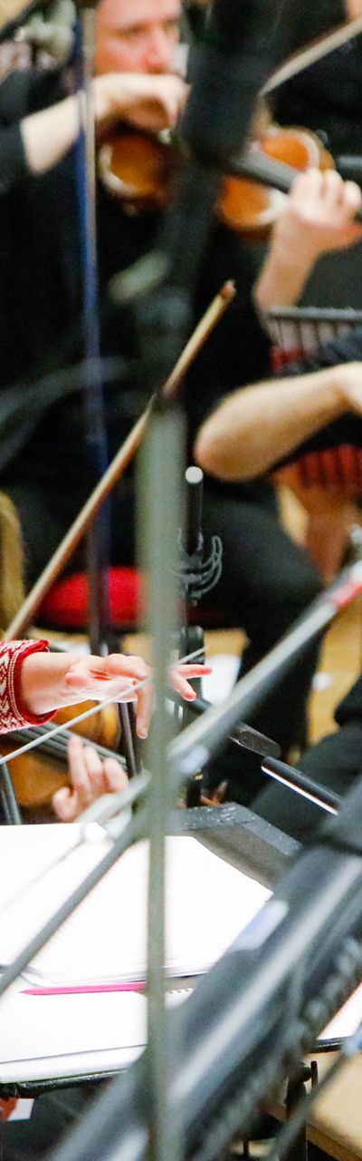 Orchestra conductor leading musicians in studio