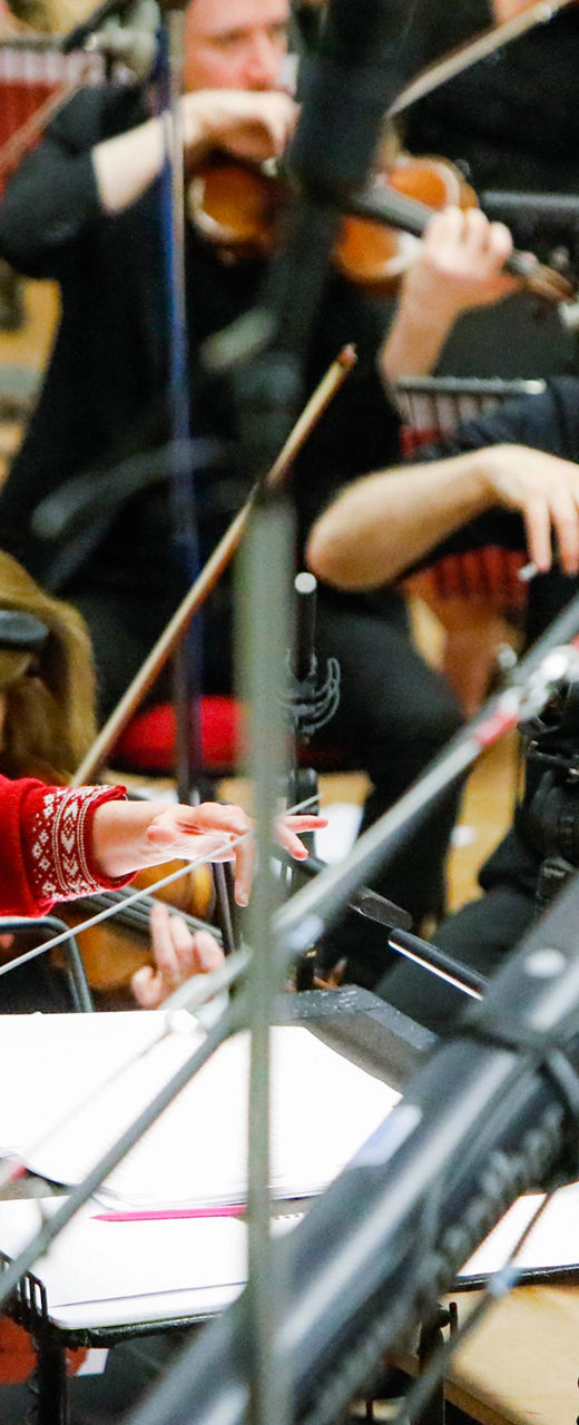 Orchestra conductor leading musicians in studio