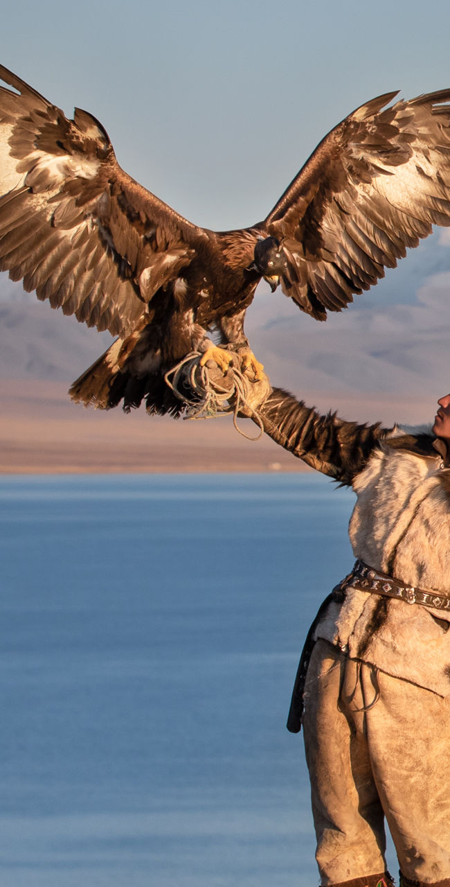 Eagle hunter by serene mountain lake