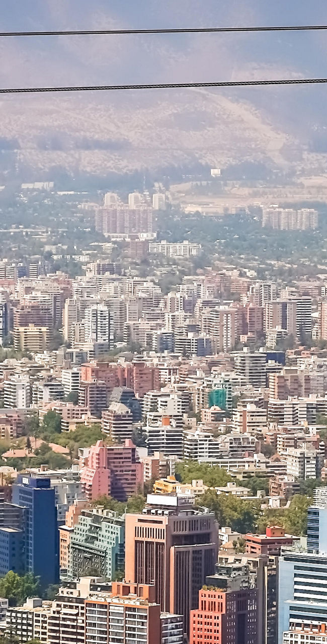 Red cable car over cityscape with mountains