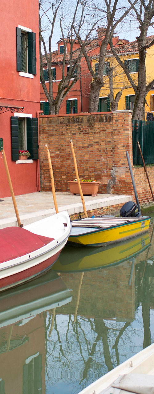 Colorful canal with boats in Burano, Italy