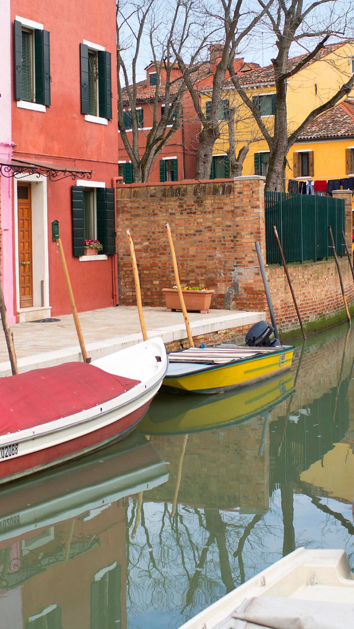 Colorful canal with boats in Burano, Italy