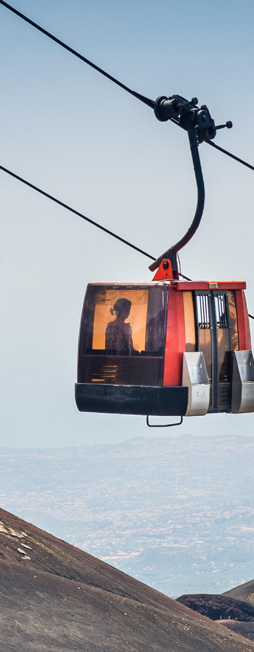 Red cable cars over volcanic landscape