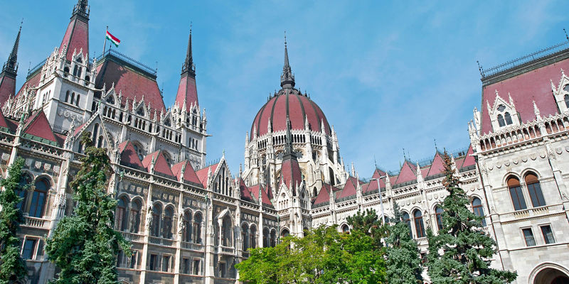Historic riverside parliament building under blue sky
