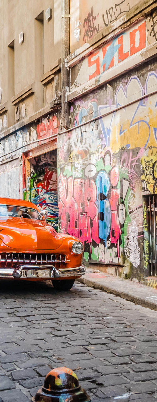 Vintage car in graffiti-covered urban alley