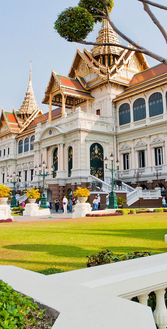 Grand palace with manicured trees in daylight