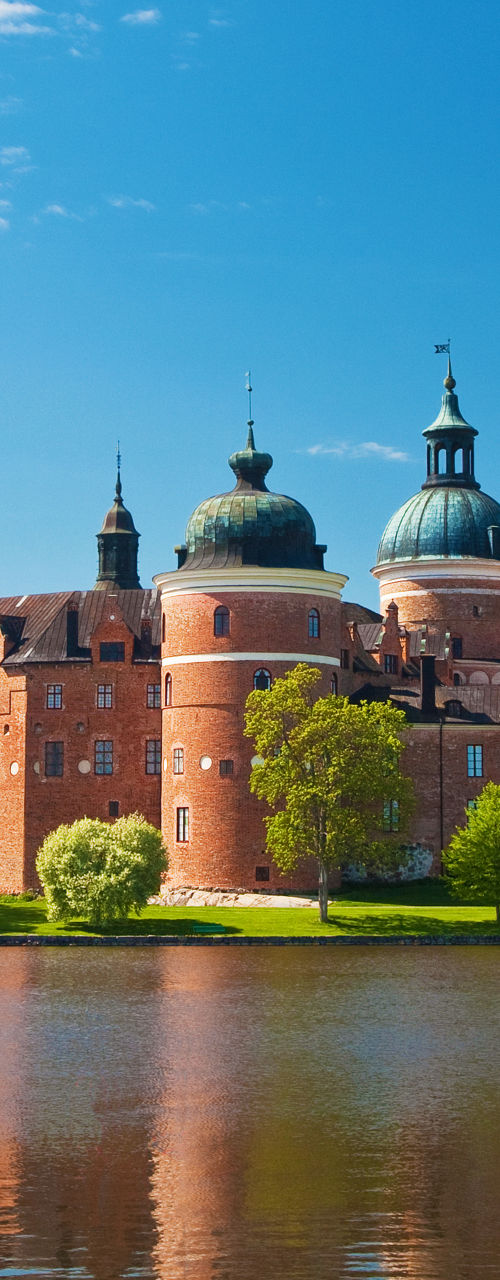 Historic castle by serene lake under blue sky