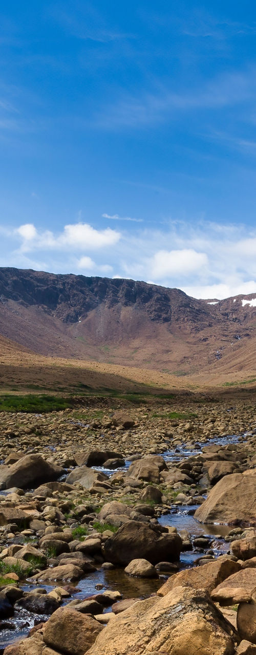 Rocky valley with stream under blue sky