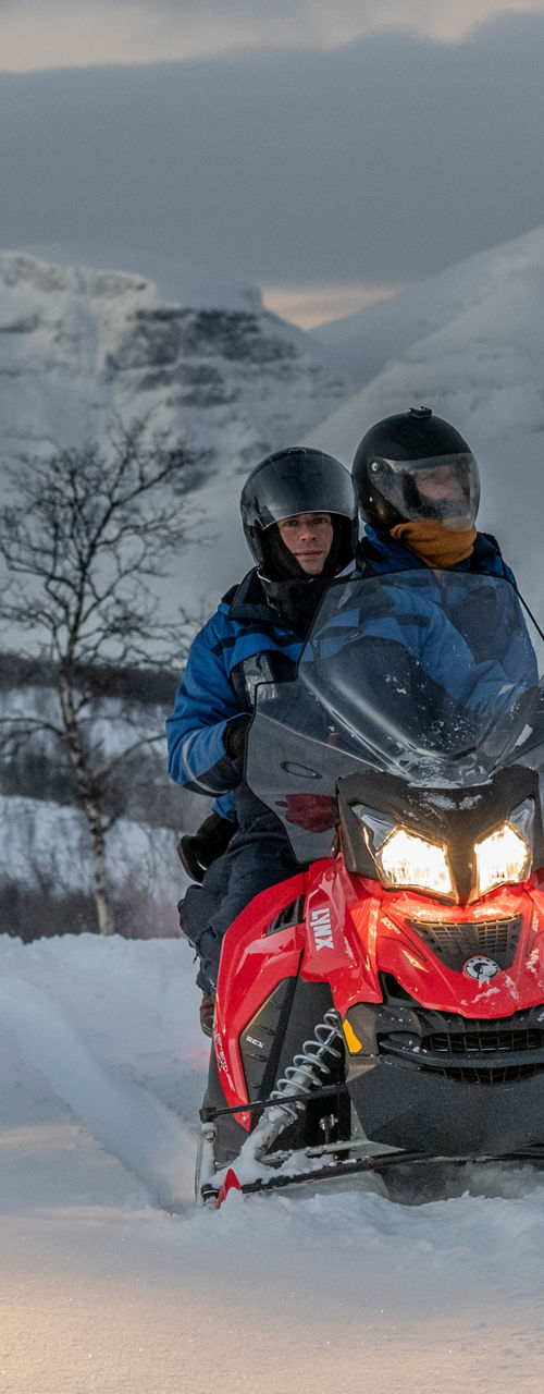 Group riding snowmobiles in snowy mountains