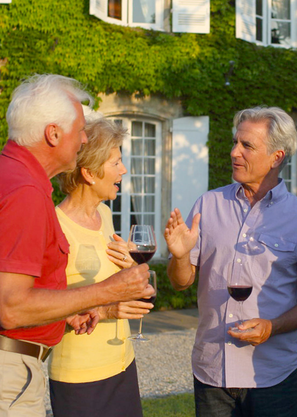 Group enjoying wine outside ivy-covered house