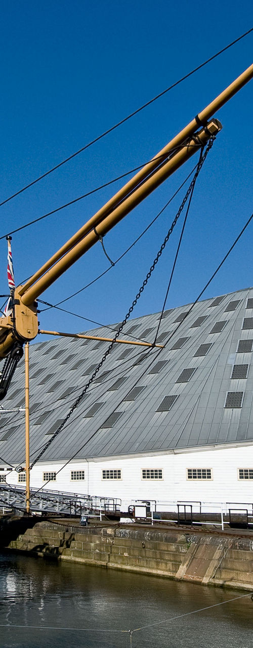 Historic ship docked near modern architecture