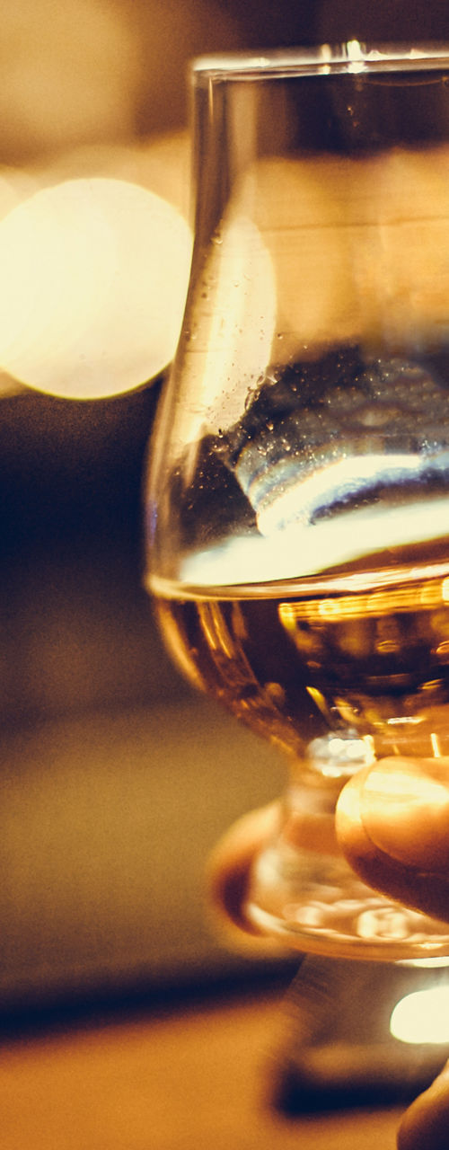 Hand holding whiskey glass in dim bar