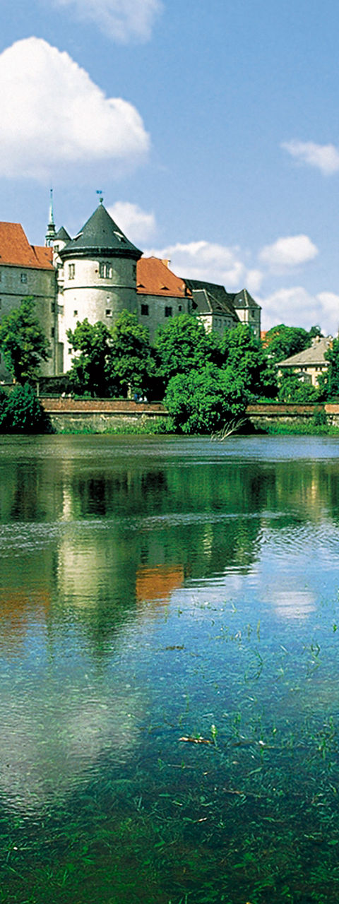 Historic castle by serene riverside landscape