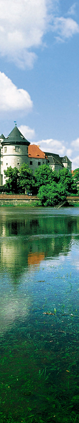 Historic castle by serene riverside landscape