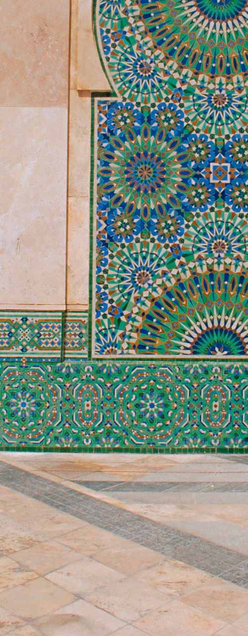 Woman reading near ornate mosque wall