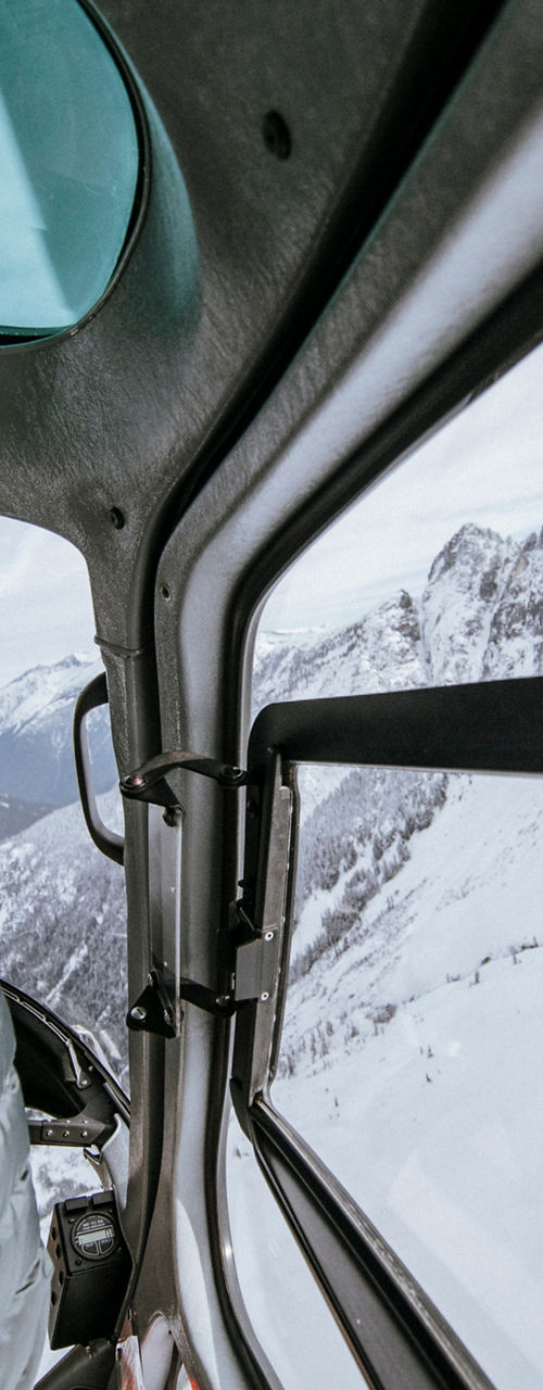Pilot navigating helicopter over snowy mountains