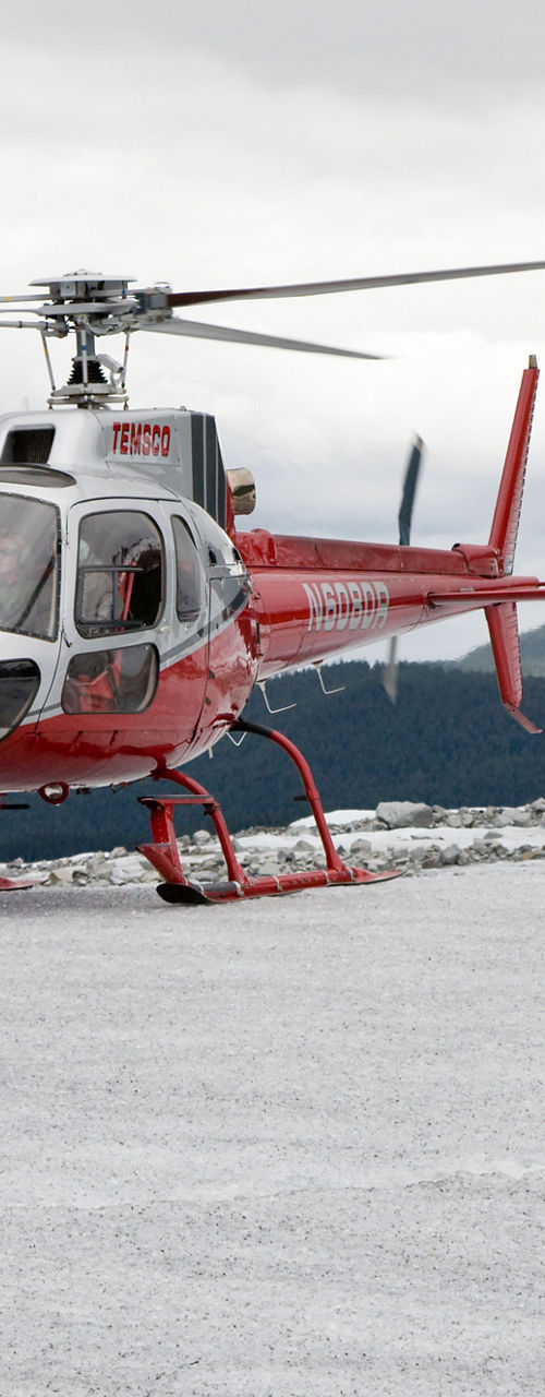 Red helicopter on snowy mountain landscape
