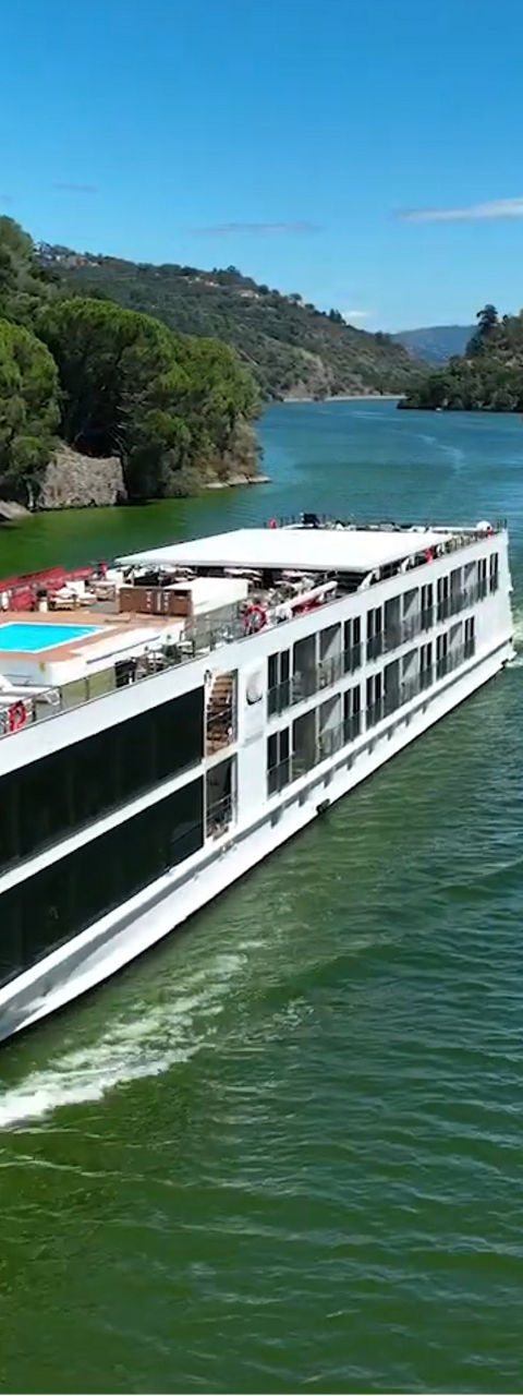Modern river cruise ship sailing through green valley