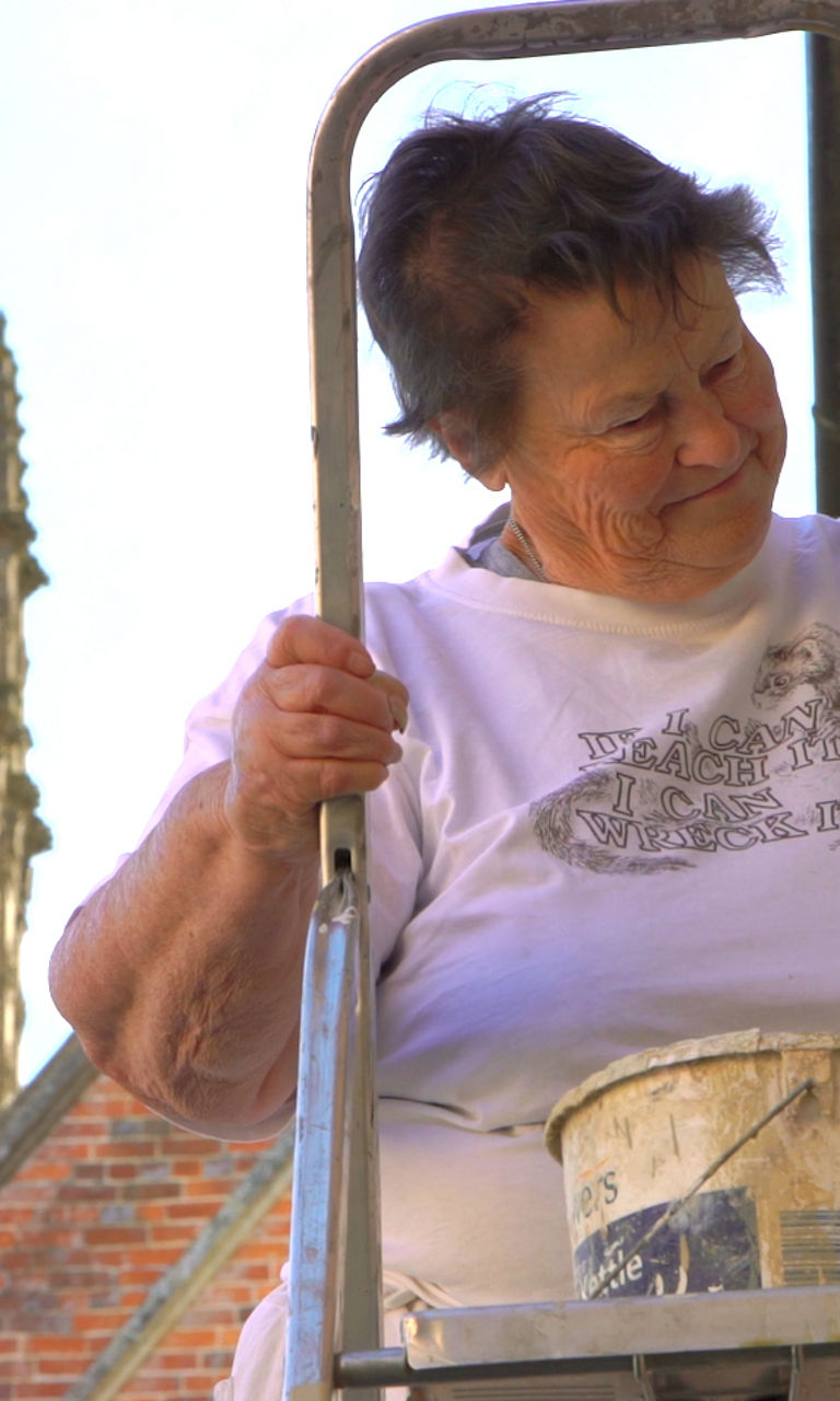 Person painting exterior near historic building