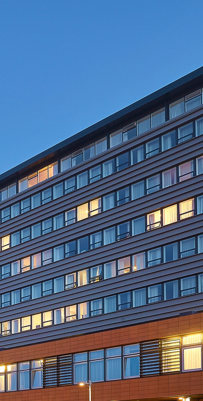 Modern hotel building at dusk with cars