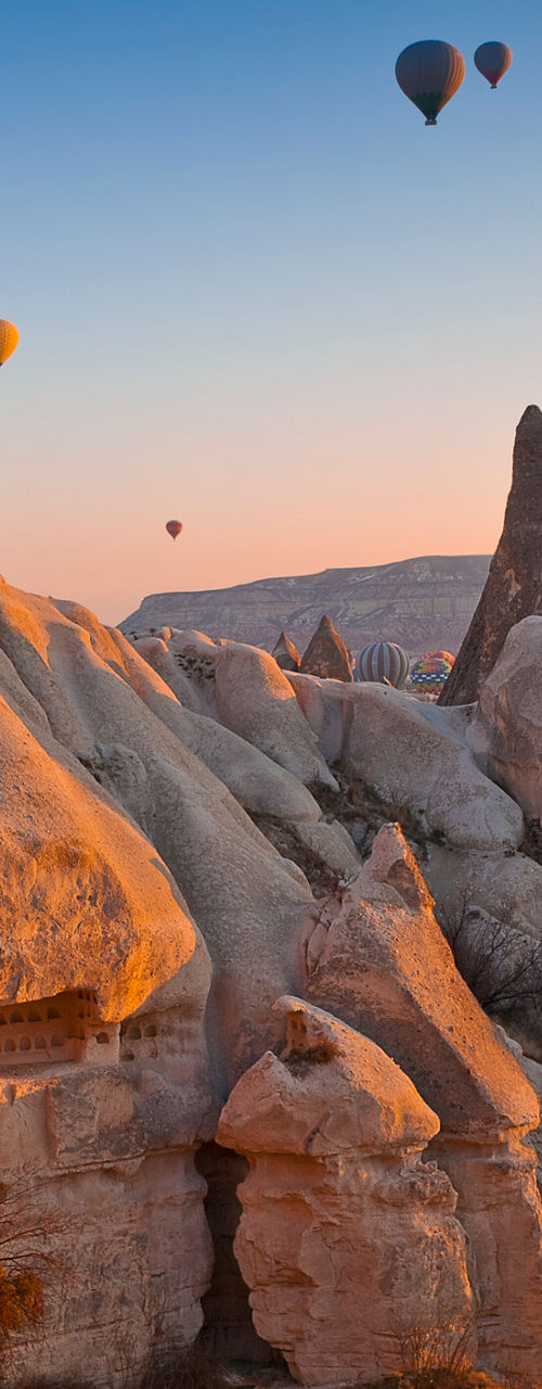 Hot air balloons over rocky Cappadocia landscape