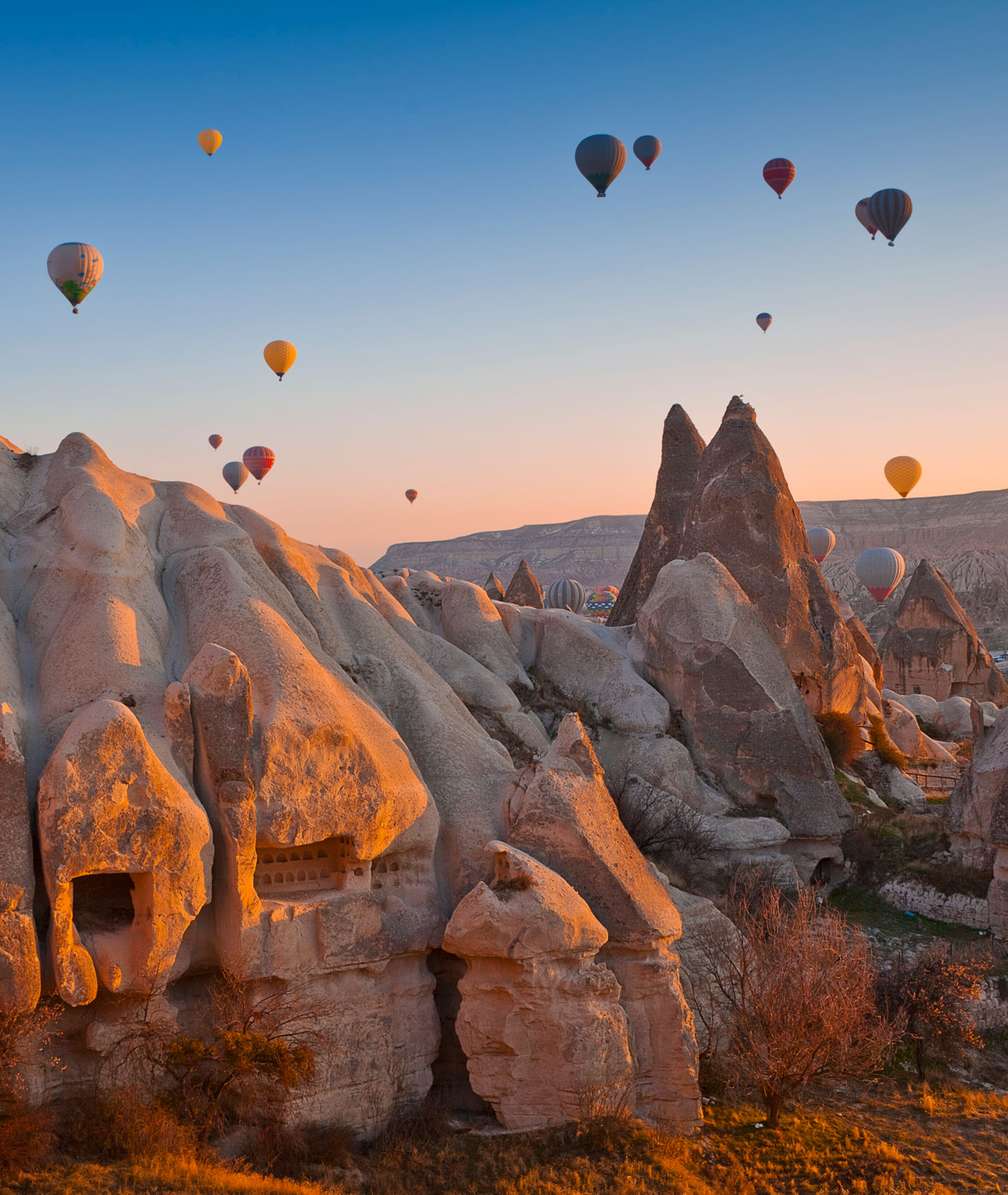 Hot air balloons over rocky Cappadocia landscape