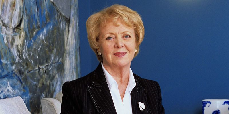 Elegant older woman seated in blue room