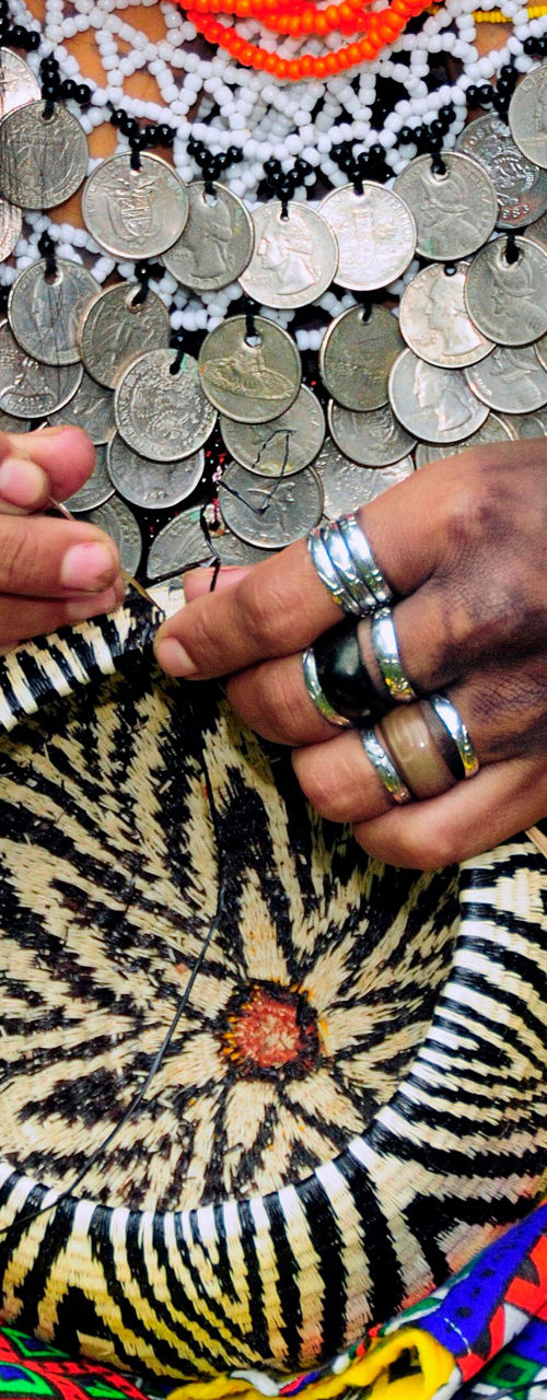 Woman weaving basket in vibrant attire