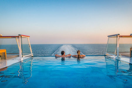 Couple relaxing in infinity pool at sea