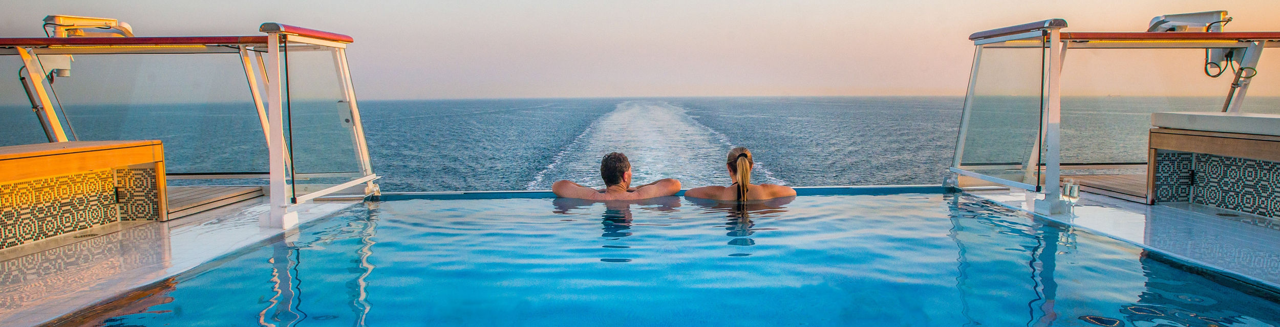 Couple relaxing in infinity pool at sea