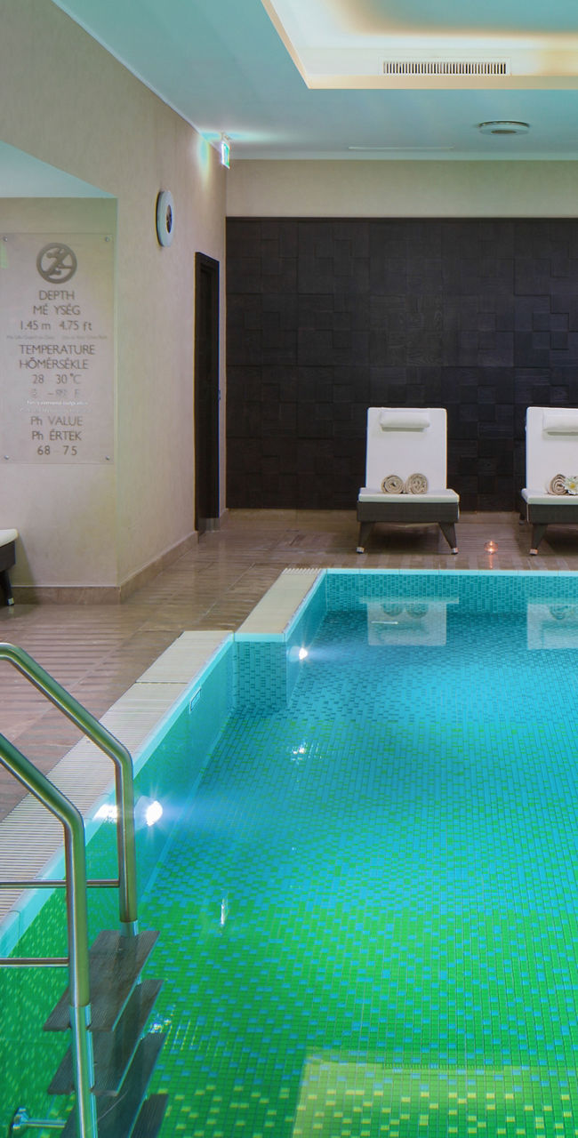 Indoor pool with lounge chairs and lighting