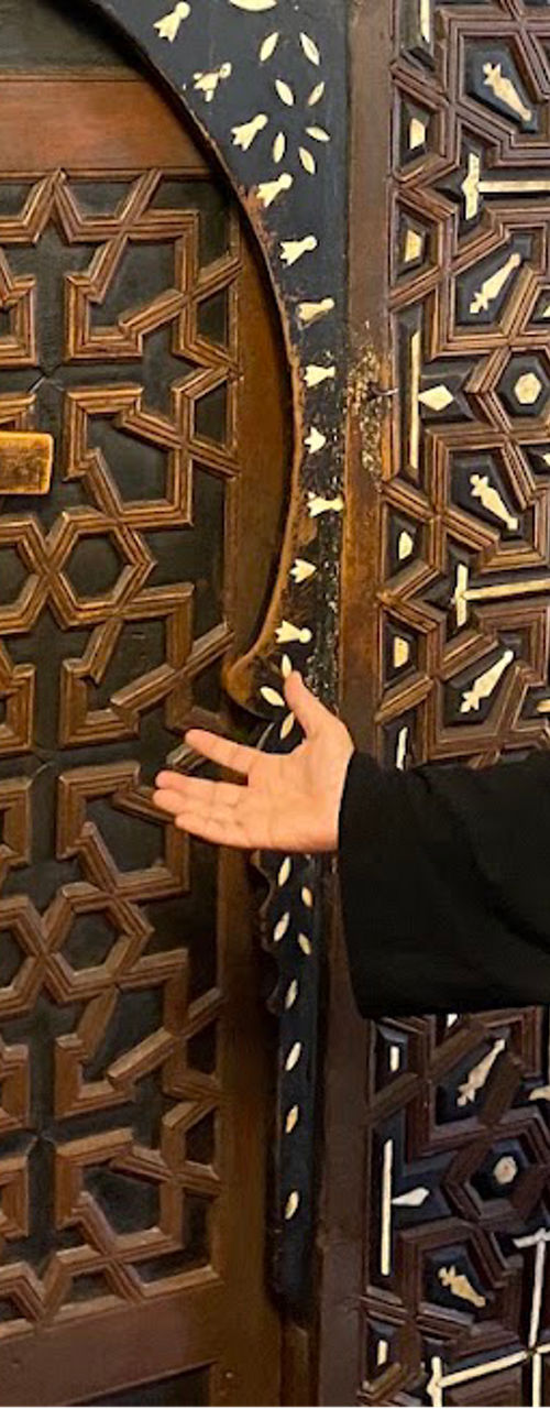 Cleric explaining ornate wooden church door