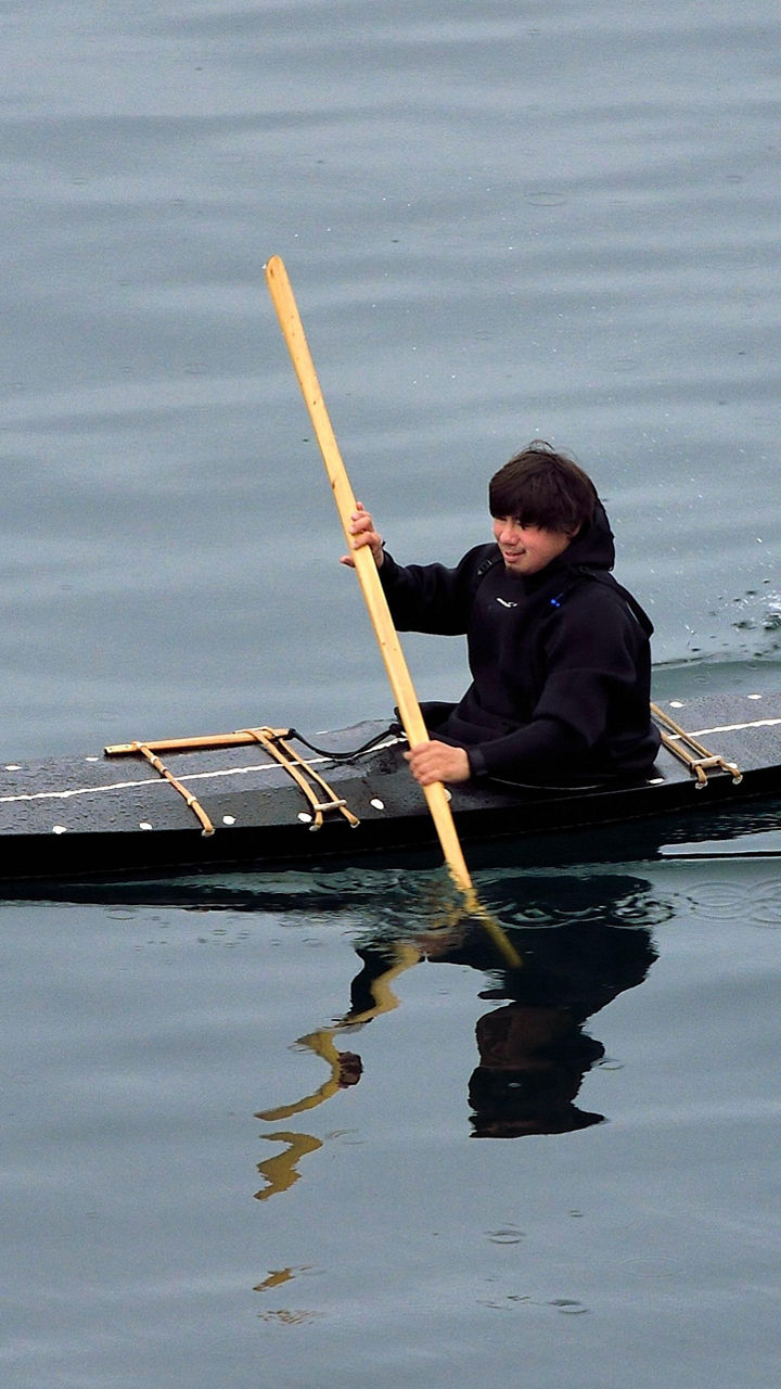 Person kayaking on calm water surface