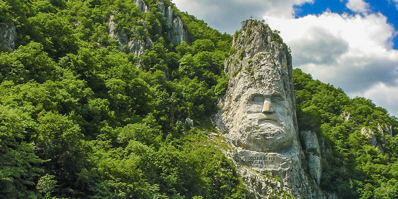 Rock sculpture by river in lush landscape