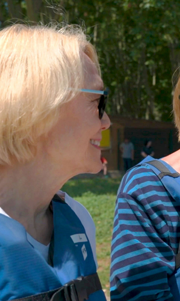 Two women wearing blue life jackets outdoors