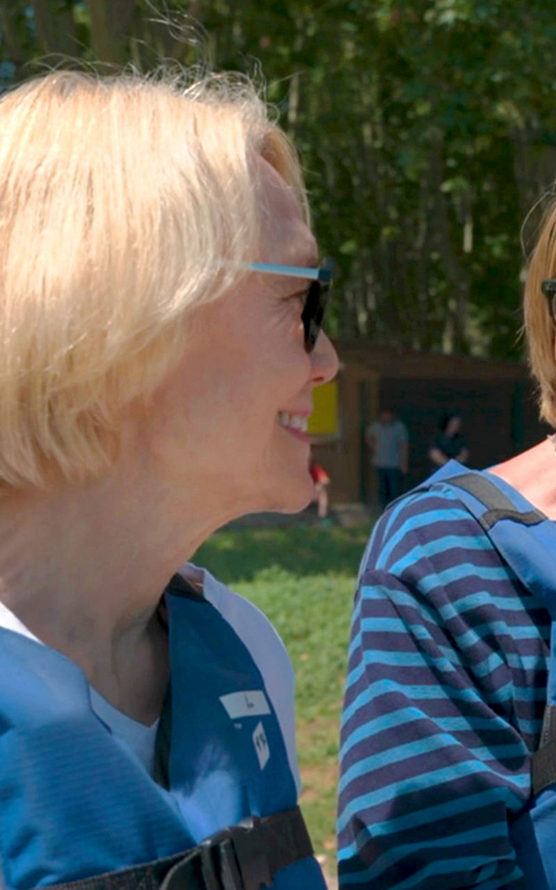 Two women wearing blue life jackets outdoors