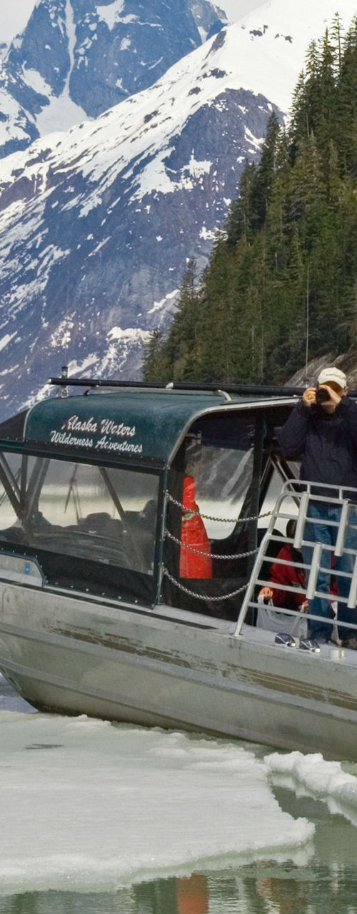 Tour boat on icy lake with mountains